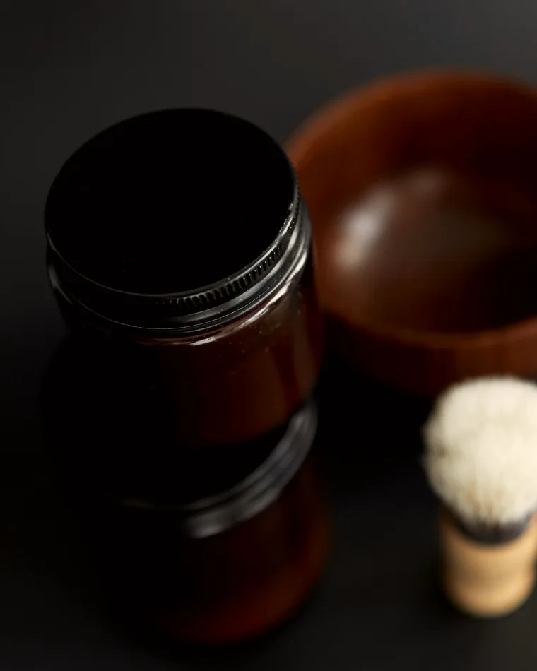 Pots de soin et blaireau de rasage sur fond sombre